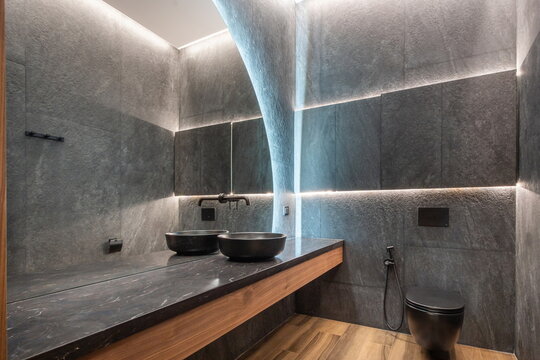 Stylish design of the bathroom, decorated in gray, with a large mirror and backlight.