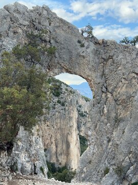 Spectacular rock arch Arcu &lsquo;e su tasaru on the trail to Cala Mariolu beach, Gulf of Orosei, Sardinia, Italy