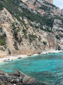 Cala Mariolu beach with a moored passenger ferry on the white pebble shore, Gulf of Orosei, Sardinia, Italy