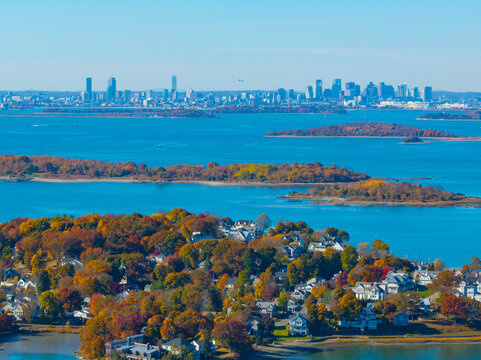 Grape Island and Peddocks Island in Hingham Bay in fall aerial view, with Hingham waterfront residential houses in near and Boston modern city skyline in far, in town of Hingham, Massachusetts MA, USA