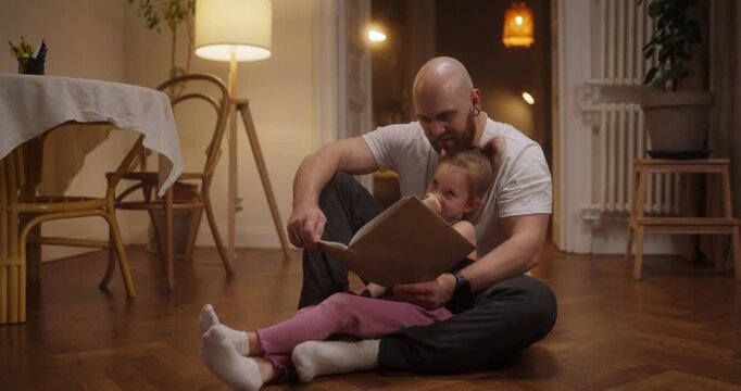 A dad and his daughter share a magical bedtime moment reading a cherished book in their cozy living room