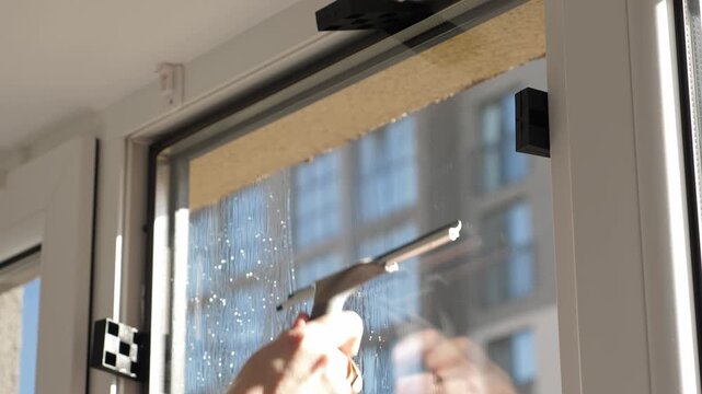 Worker installing and smoothing tint film on window at home. Man washing windows before tinting
