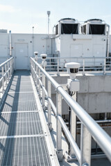 Naklejka premium Security sensors line rooftop walkway at industrial facility with metal railings
