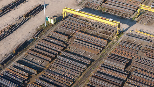 Aerial view of PD Ports industrial site with stacks of steel beams and a yellow gantry crane in Scunthorpe, England, United Kingdom.