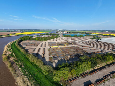 Aerial view of PD Ports industrial storage facility with stacks of steel pipes and gantry cranes near the river bank in Scunthorpe, England, United Kingdom.