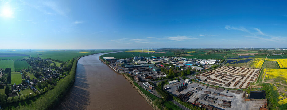 Aerial view of Flixborough Industrial Estate situated along the River Trent with surrounding green fields and yellow rapeseed under a clear blue sky Flixborough, England, United Kingdom.