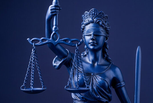 Dark blue statue of lady justice with scales and sword