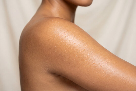 Close up of woman shoulder with glistening perspiration on skin