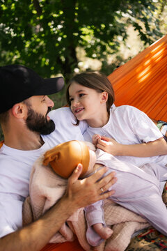 Father and daughter share warm moment together while holding baby in outdoor tent surrounded by trees