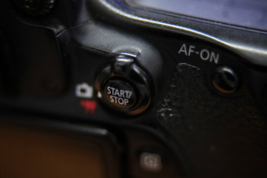 Macro close-up of start and stop button on professional black digital camera.