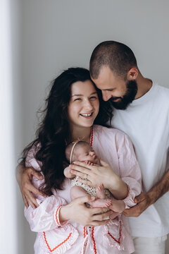Family embracing newborn baby in soft indoor light, gentle moment of love and connection