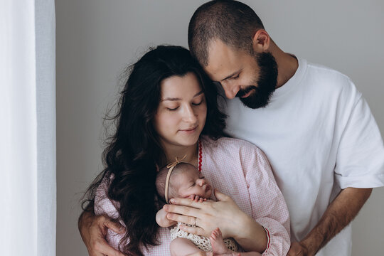Newborn baby held by parents in soft natural light, intimate family moment at home
