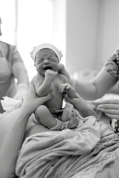 Newborn baby cries softly while being held by parents in hospital room after birth