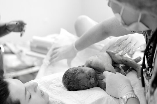 Newborn baby rests peacefully as mother smiles softly beside her in quiet hospital room moment