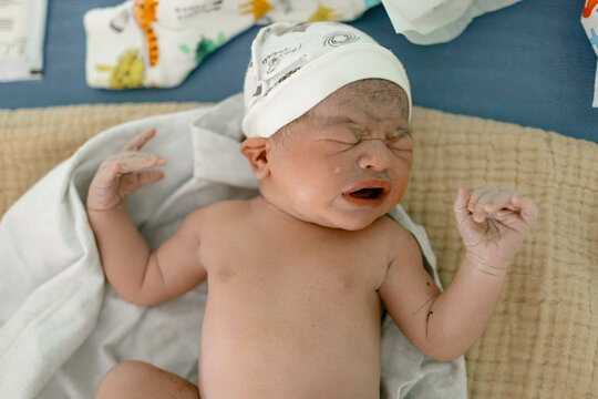 Newborn baby sleeps peacefully wrapped in soft blanket on cozy textured surface