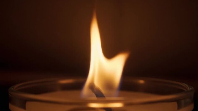 Close-up of a single candle flame burning in the dark, warm glow, peaceful atmosphere