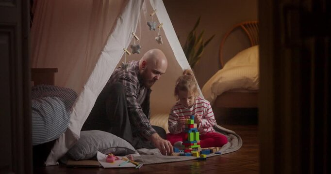 A child and a parent create fun structures with bright building blocks in a warm, inviting indoor setting