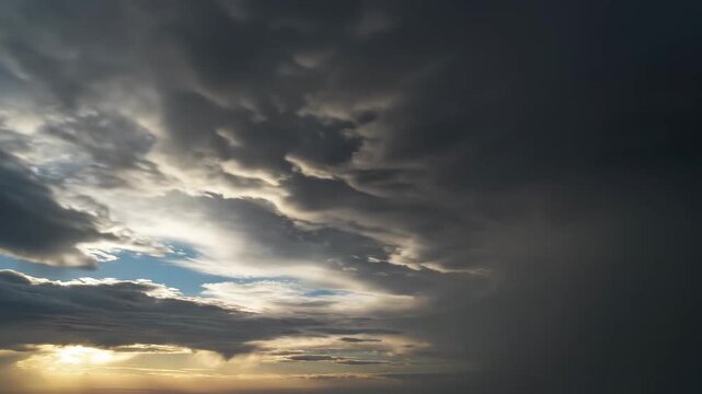 Dramatic Stormy Sky with dark clouds and golden sunset light breaking through for cinematic background and weather forecast visuals.