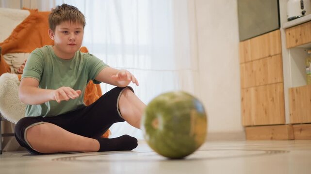 Caucasian teen at home kitchen floor holding melon, contemplative pause as young home cook imagines recipe ideas soft natural light, rug and chair in background, casual socks and relaxed posture