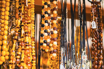 Amber necklace hanging on display in market stall. Collection of jewelry made from fossils beads. Accessory for fashion style and traditional decorative ornament. © Anton Dios