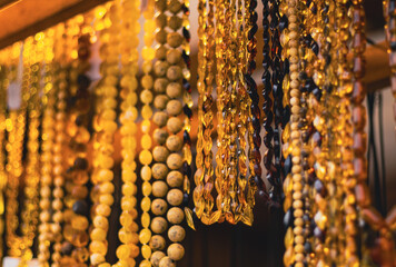 Amber necklace hanging on display in market stall. Collection of jewelry made from fossils beads. Accessory for fashion style and traditional decorative ornament. © Anton Dios