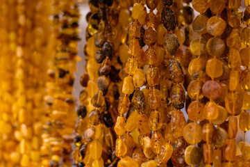 Amber necklace hanging on display in market stall. Collection of jewelry made from fossils beads. Accessory for fashion style and traditional decorative ornament. © Anton Dios