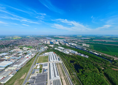 Aerial view of the industrial landscape and port facilities of Goole, featuring large warehouses, the River Ouse, and surrounding green fields under a clear blue sky in Goole, England, United Kingdom.