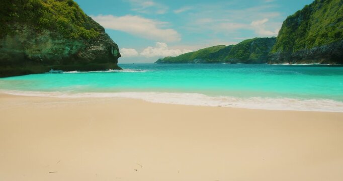 Bright turquoise ocean water meeting white sand shore at Kelingking beach Bali