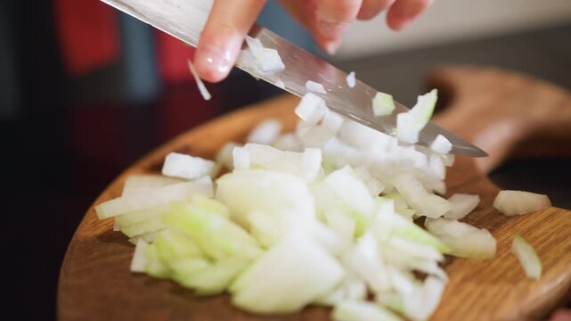 Efficient chef swiftly dices onion on wood. Home cook quickly chops onions on wooden surface for meal. Busy chef expertly slices onion on wooden board to prepare speedy dinner dish