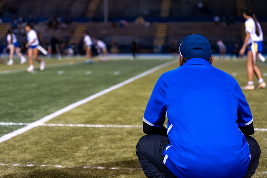 Flag football coach squats down and focuses on game play