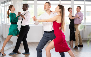 Fototapeta premium Elegant couples dancing tango, enjoying dance moves in dance salon