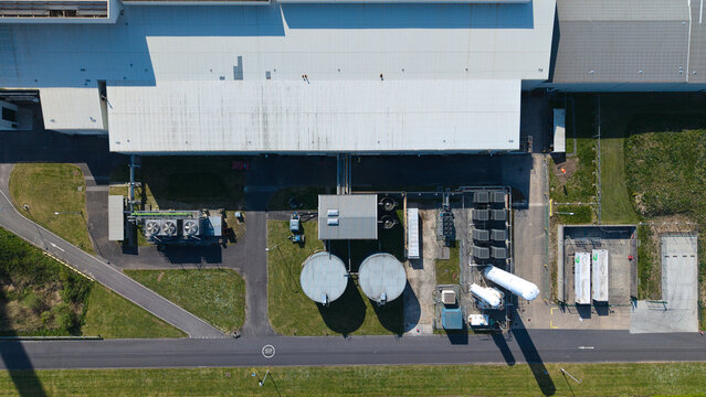 Aerial view of an industrial glass manufacturing facility with large warehouse roofs, storage silos, and cooling systems Goole, England, United Kingdom.