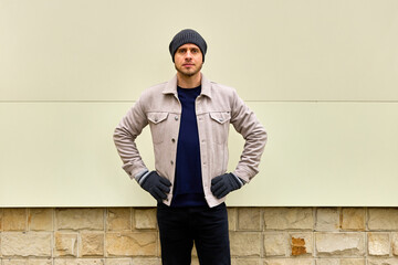 Man stands confidently against plain wall backdrop © Iurii Gagarin
