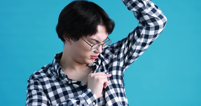 Young guy suffering from sweating on light blue background