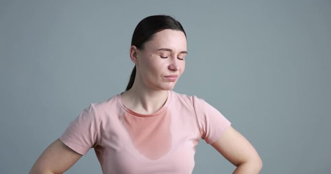 Woman suffering from sweating on grey background