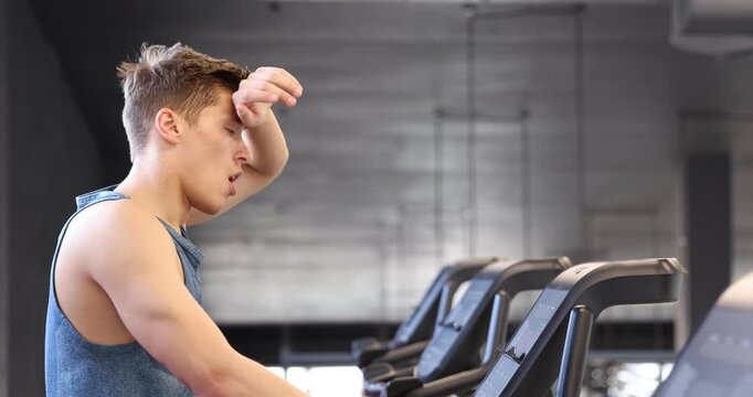Man sweating while training on stationary bicycles in gym