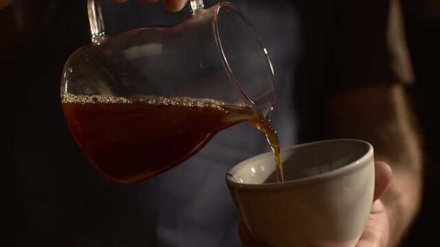 Fresh coffee being poured into cup, smooth liquid flow, steam rising, cinematic slow motion, cozy specialty coffee mood.