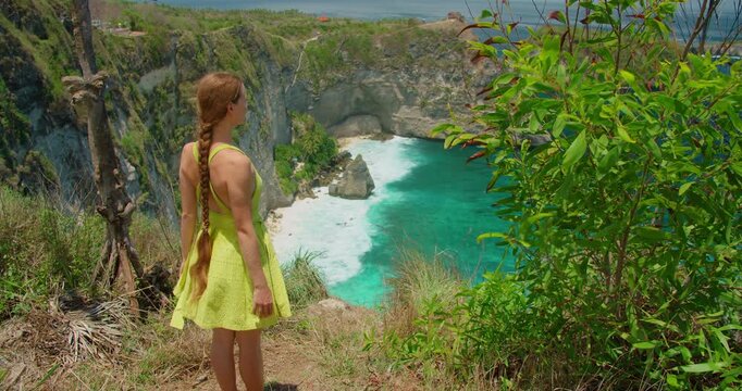 Traveler woman looking at beautiful coastal scenery from Nusa Penida cliff edge