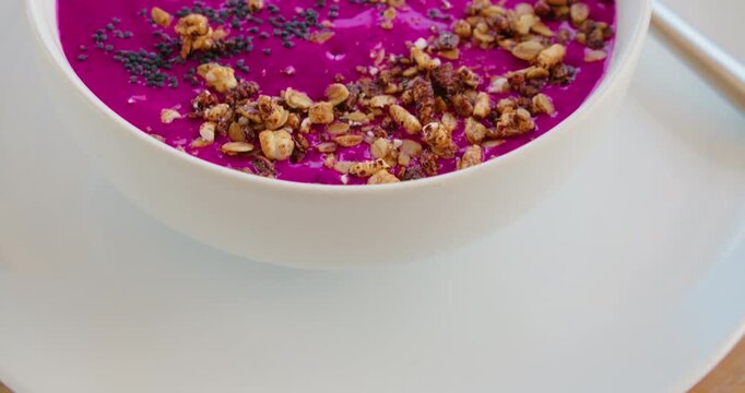 Close up crunchy granola and black seeds chia on pink dragon fruit puree or smoothie