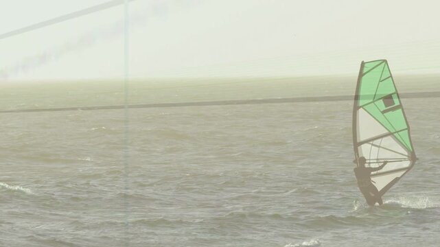 Male windsurfer in sports adjusting boom and weight, wind catching sail to maintain balance