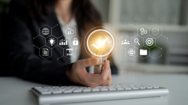 A business professional holds a light bulb symbolizing innovative ideas amidst digital graphics representing technology and growth strategies in a modern office environment. Gantry