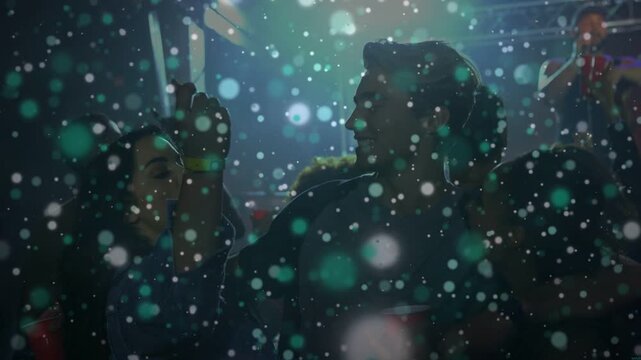 Trio at gig talking as lights, singer sparking smiles, flakes hiding faces, red cups, man turning