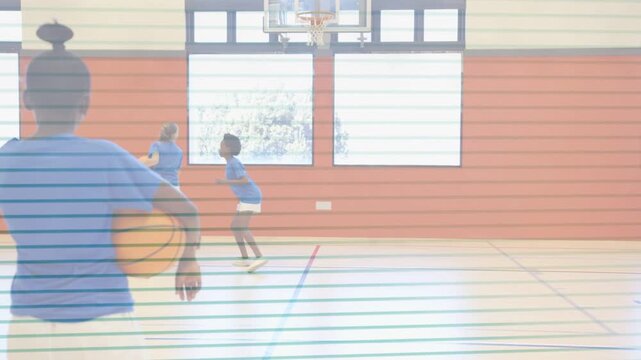 Schoolgirl holding ball, watching teammates entering, dribbling toward hoop, practicing layup