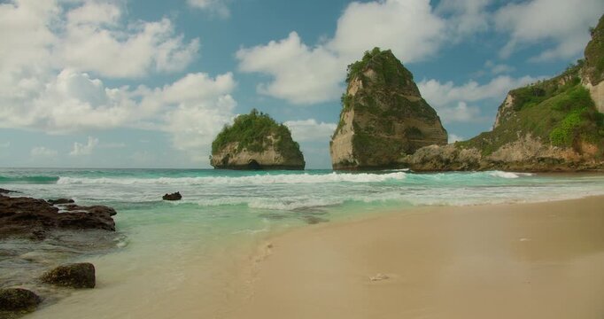 Beautiful shoreline view with white sand and towering rock formations in Nus Penida Bali island