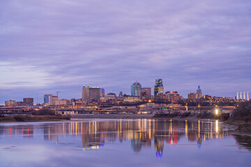 Naklejka premium The skyline of Kansas City glows under a purple twilight sky.