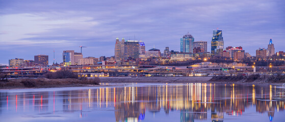 Fototapeta premium The Kansas City skyline glows at dusk beside the river.