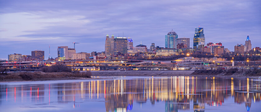 The Kansas City skyline glows at dusk beside the river.