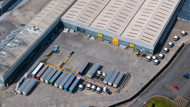 Aerial view of a large industrial warehouse and distribution center with rows of parked semi-trucks in the loading yard in Knottingley, England, United Kingdom.