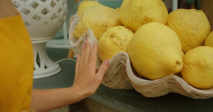 Woman hand touches giant lemons in shell bowl at seaside cafe on warm summer day