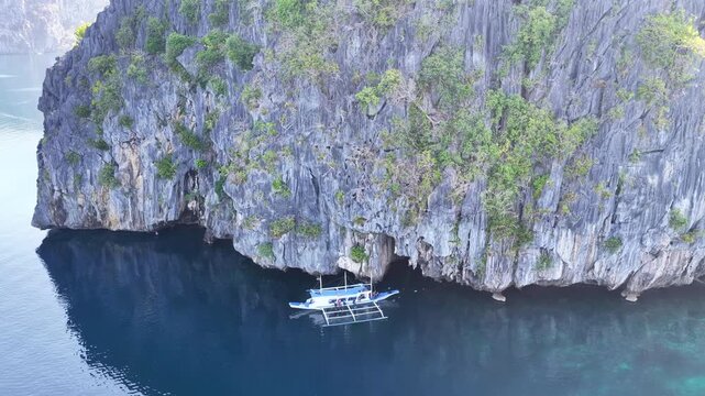 A small bangka drifts at the mouth of Cathedral Cave found in Pinisil Island, Philippines. This beautiful geologic marvel is a famous tourist attraction near El Nido, Palawan.